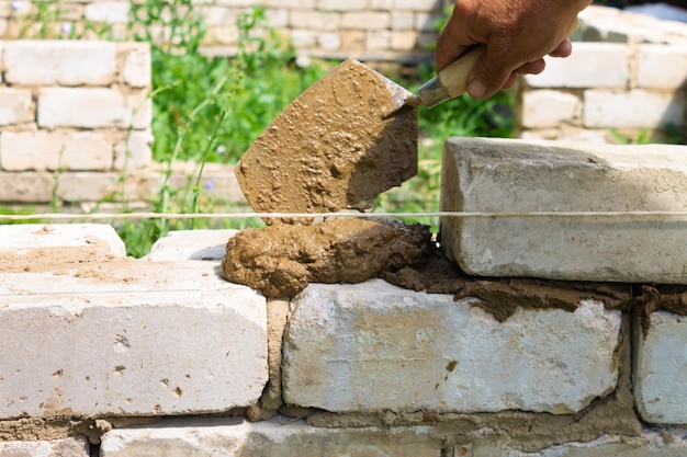 The bricklayer applies mortar to the wall with a trowel Technology of laying buildings from cement