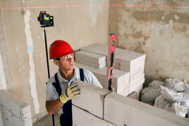 Bricklayer or mason lays bricks to construct wall of autoclaved aerated concrete blocks brickwork