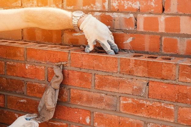 Bricklayers laying bricks on mortar