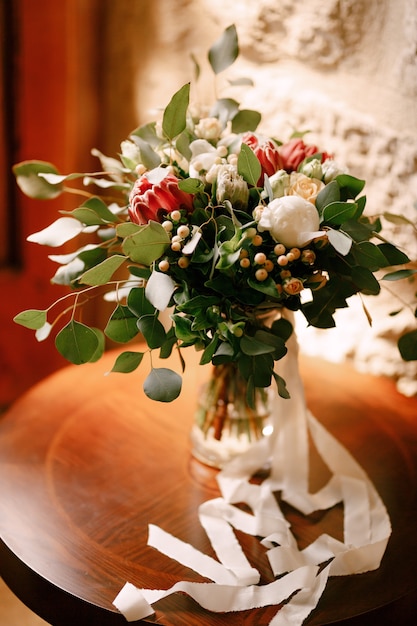 Bridal bouquet in a glass vase on a round wooden table