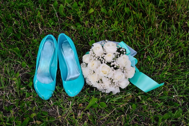 Bridal bouquet and turquoise shoes on green grass