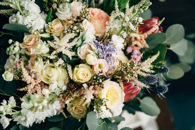 Bridal bouquet of white and cream roses branches of eucalyptus tree protea eryngium and delphinium