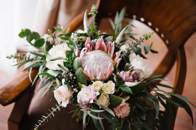 Bridal bouquet of white and pink roses protea eucalypt tree branches veronica and peonies on the