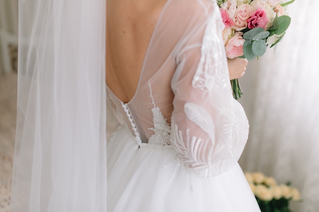 Bride in beautiful dress holds a wedding bouquet.