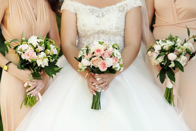 Bride and bridesmaids holding with wedding bouquets on their hands