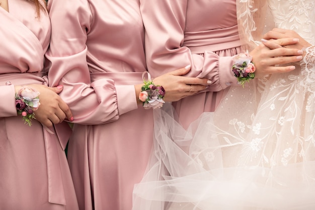 Bride and bridesmaids in pink dresses holding hands at wedding day