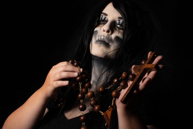 Bride cadaver with black veil holding a large rosary black background, Low Key portrait, selective focus.