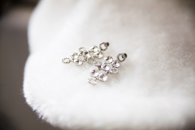 Bride earrings lie on white cape closeup