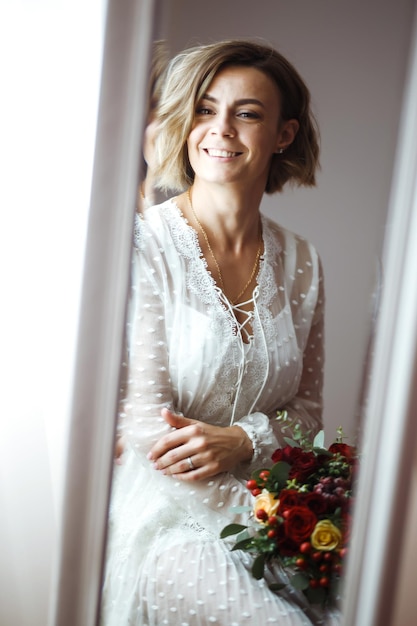 Bride in elegant white dress looking in mirror The bride smiles and poses in front of the mirror