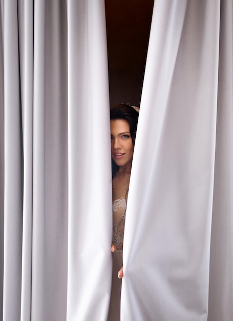 Bride flirting and covering face with curtains