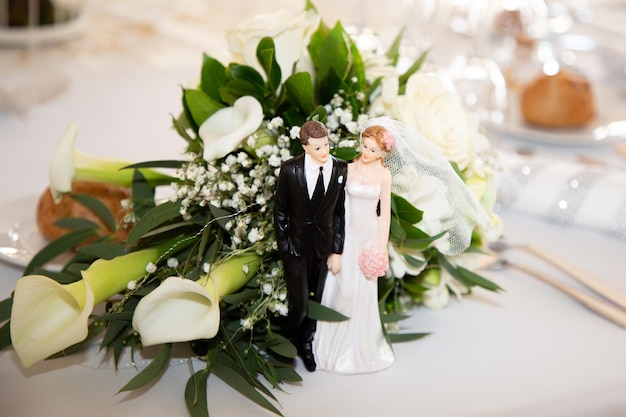 Bride flowers bouquet placed on the reception table with figurines representing the wedding couple