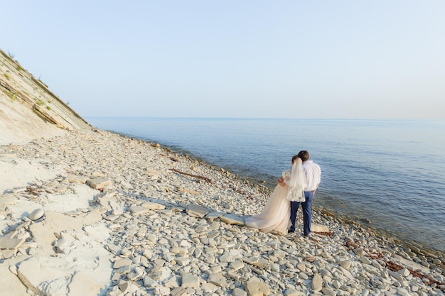 Bride and groom are hugging and looking at the sea