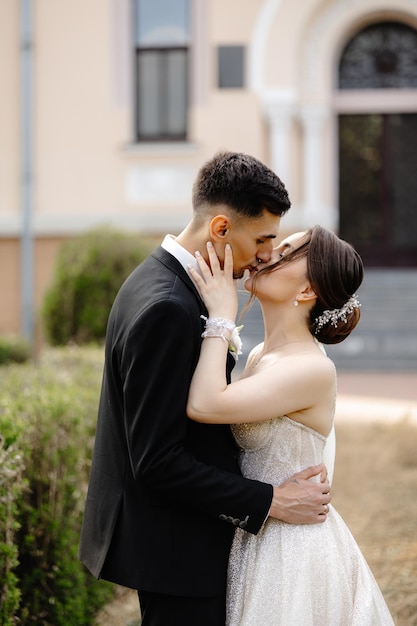 a bride and groom are kissing in front of a building