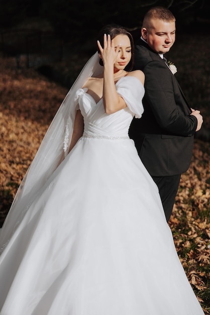 A bride and groom are posing for a picture in a field