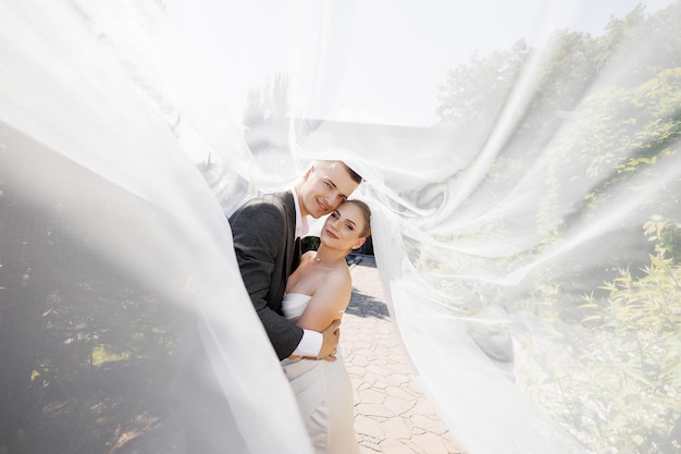 Photo a bride and groom are posing for a picture under a white veil