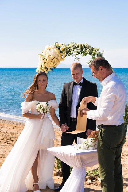 Photo a bride and groom are standing on a beach