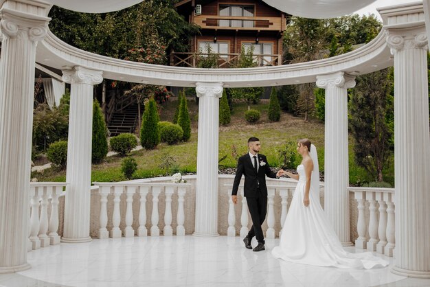 Photo a bride and groom are standing in front of a white archway