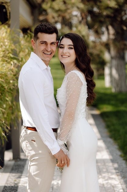 A bride and groom are standing in a park