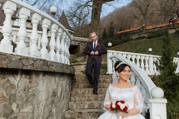 Photo a bride and groom are standing on a stone staircase in front of a white building