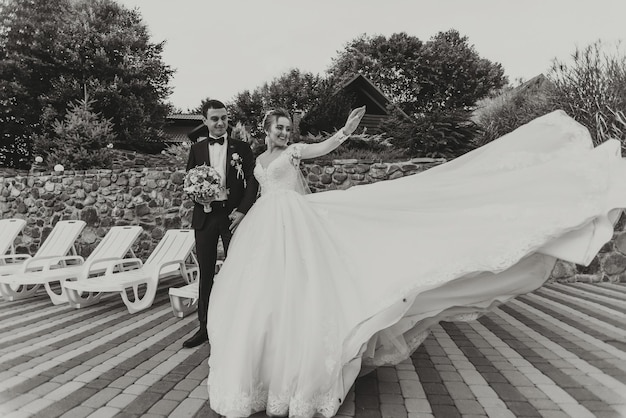 A bride and groom are walking down a path with a white dress on the bride