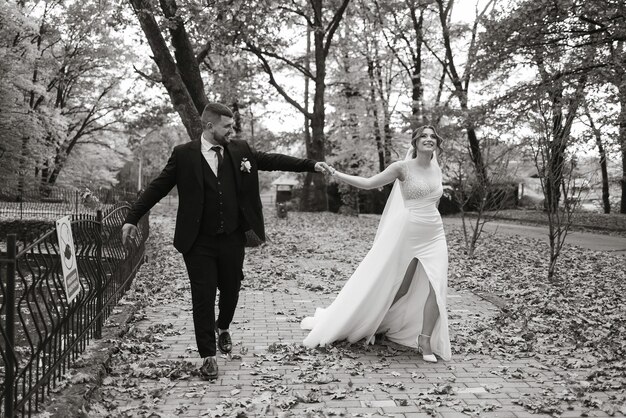 A bride and groom are walking down a path in the woods