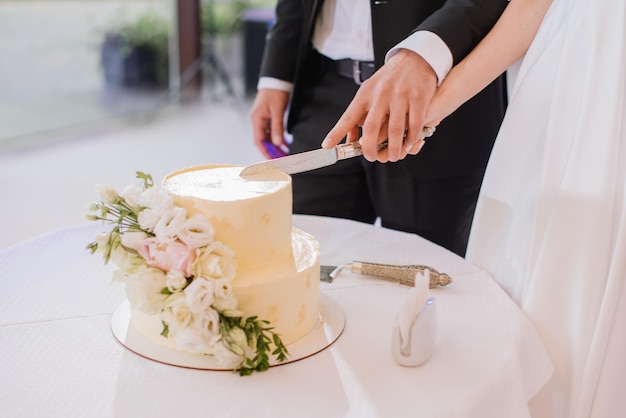 Bride and groom cuts a beautiful white cake at the banquet Closeup view