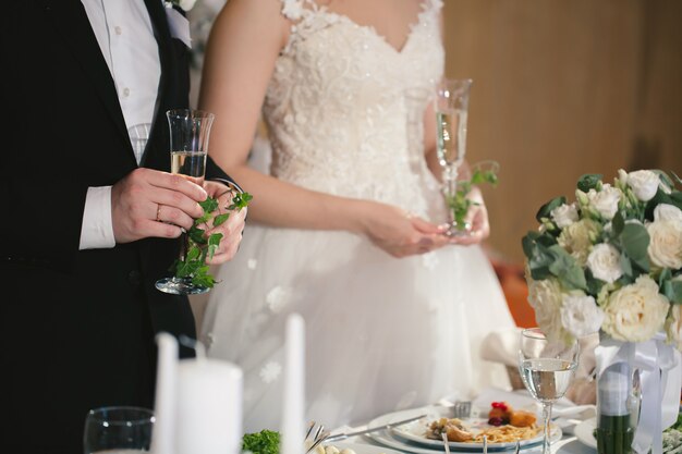 Bride and groom hold crystal glasses filled with champagne