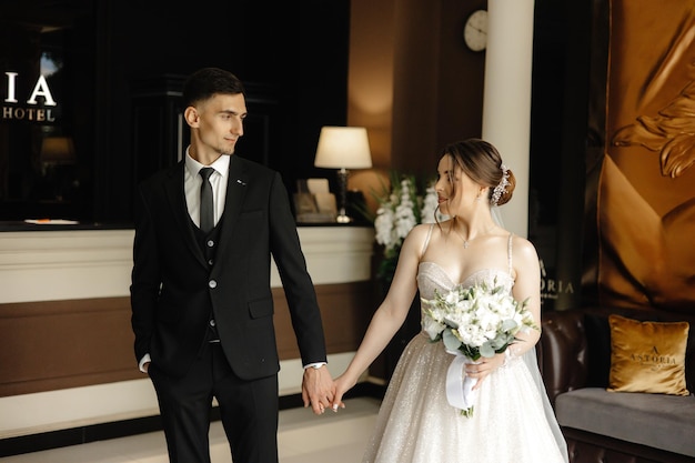 a bride and groom hold hands in front of a window