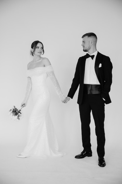 Photo a bride and groom hold hands and pose for a photo