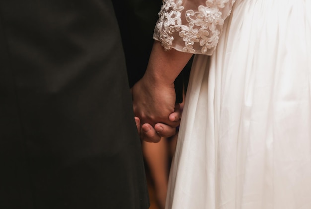 A bride and groom hold hands at their wedding.