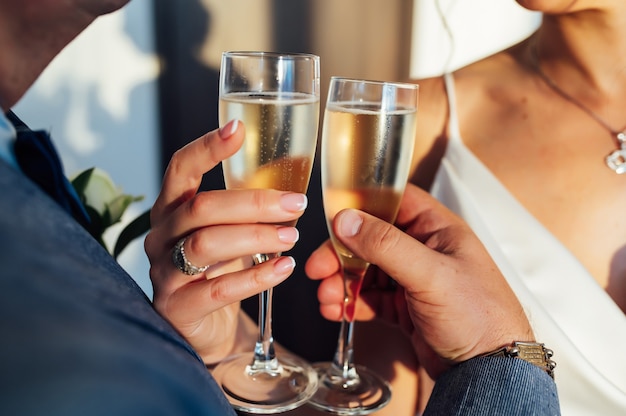 Bride and groom hold in their hands glasses with wine