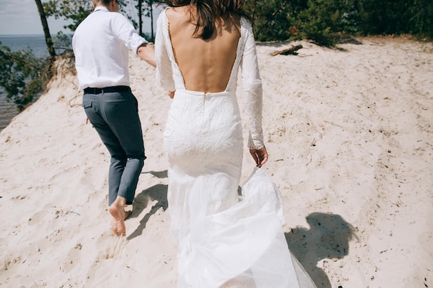 The bride and groom holding hands running on the sea beach The concept of love