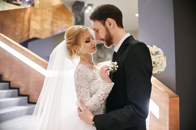 Bride and groom hugging and kissing while standing on the stairs.