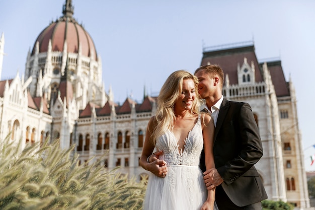 Bride and groom hugging in the old town street. Wedding couple in love. Luxury rhinestone dress.