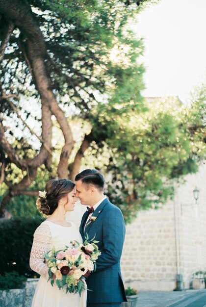 Bride and groom hugging with their foreheads touching under a tree