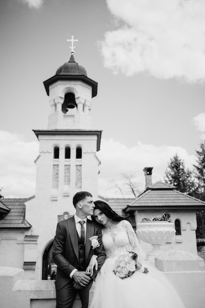 A bride and groom kiss in front of a church