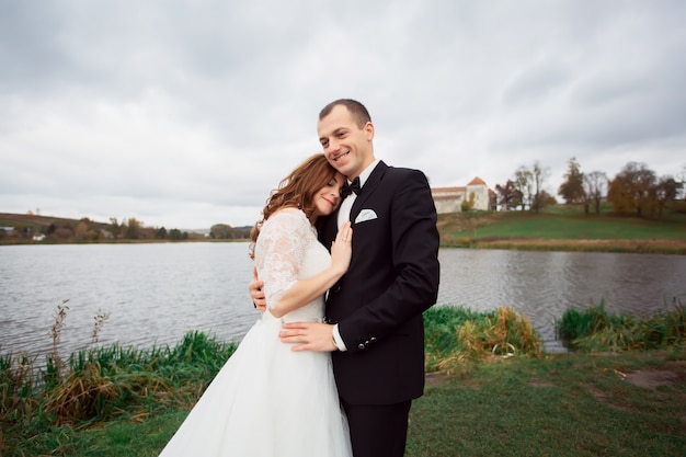 Bride and groom outdoors park under trees arc