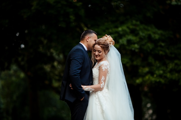 Bride and groom in a park kissing.couple newlyweds bride and groom at a wedding in nature green forest are kissing photo portrait.Wedding Couple