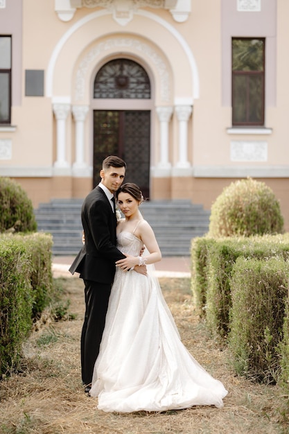 a bride and groom pose in front of a pink building