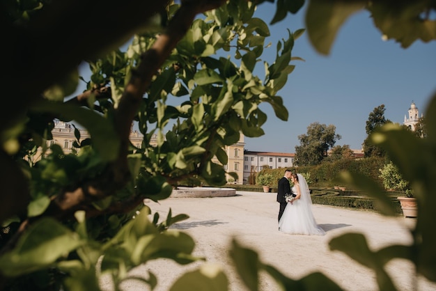 A bride and groom pose for a photo in front of a church