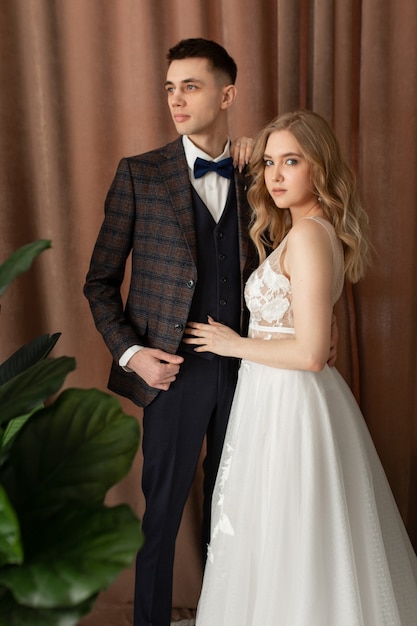 Bride and groom posing on a light brown curtain background