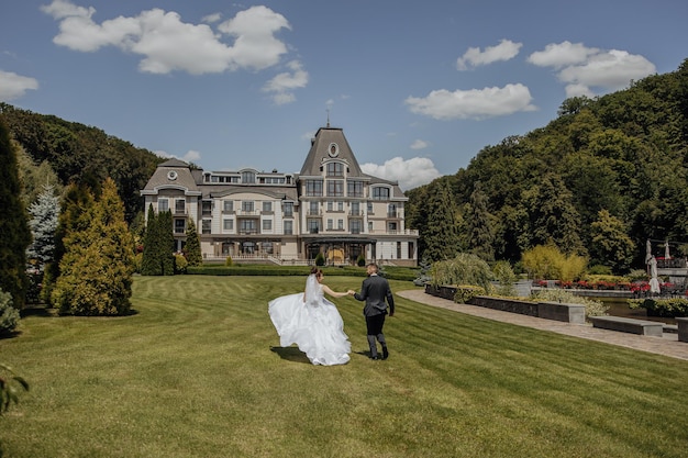 The bride and groom run through a picturesque field on the wedding day in the background