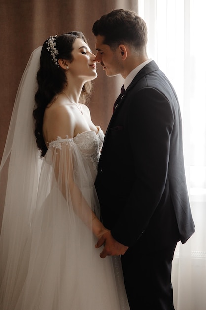 Bride and groom share a kiss in front of a window