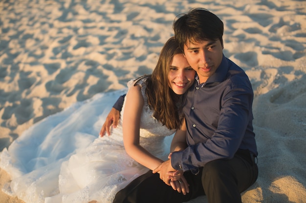 Bride and groom sit on the sand