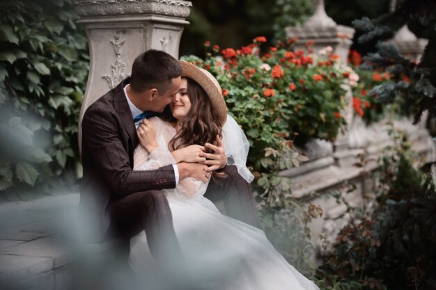 bride and groom sit on the steps in the vintage garden