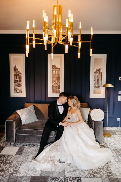 Bride and groom sitting on a couch in a blue room