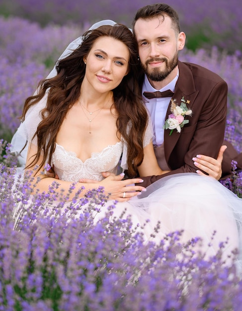 Bride and groom sitting in field with purple flowers