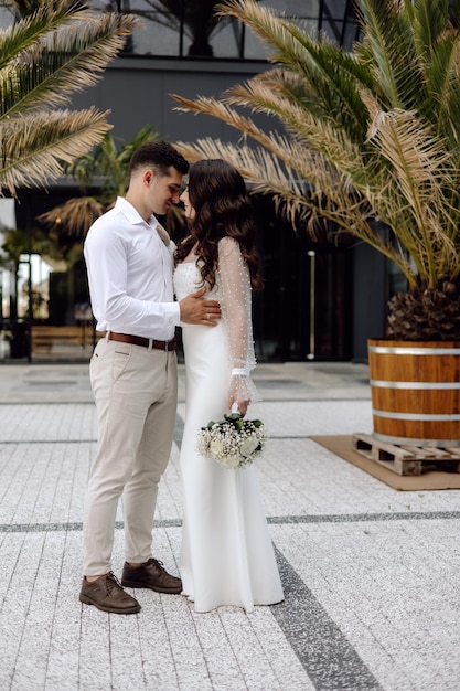 A bride and groom stand in front of a barrel barrel barrel with palm trees in the background.