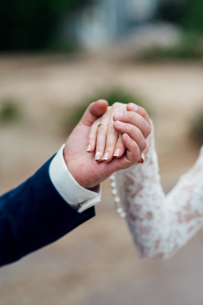 The bride and groom tenderly hold hands between them love and relationships