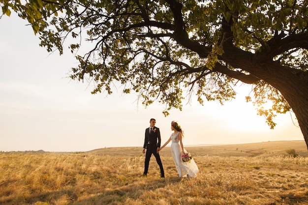 The bride and groom walk at sunset.